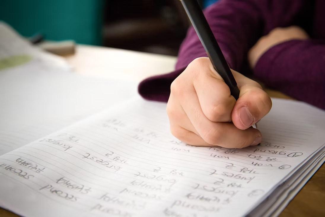 Close-up of a pupil writing vocabulary notes by hand